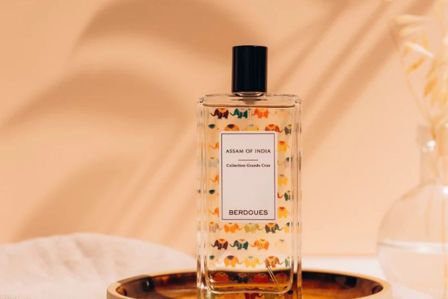 Flacon de parfum Berdoues Assam of India de la collection Grands Crus posé sur un plateau doré dans un décor lumineux et épuré