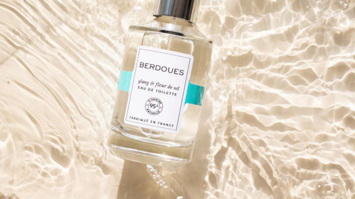 Flacon d’eau de toilette Berdoues “Ylang & fleur de sel” posé sur une surface d’eau ensoleillée, illustrant la fraîcheur et l’authenticité du slow parfum.